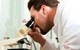 Mann analysiert mit Mikroskop